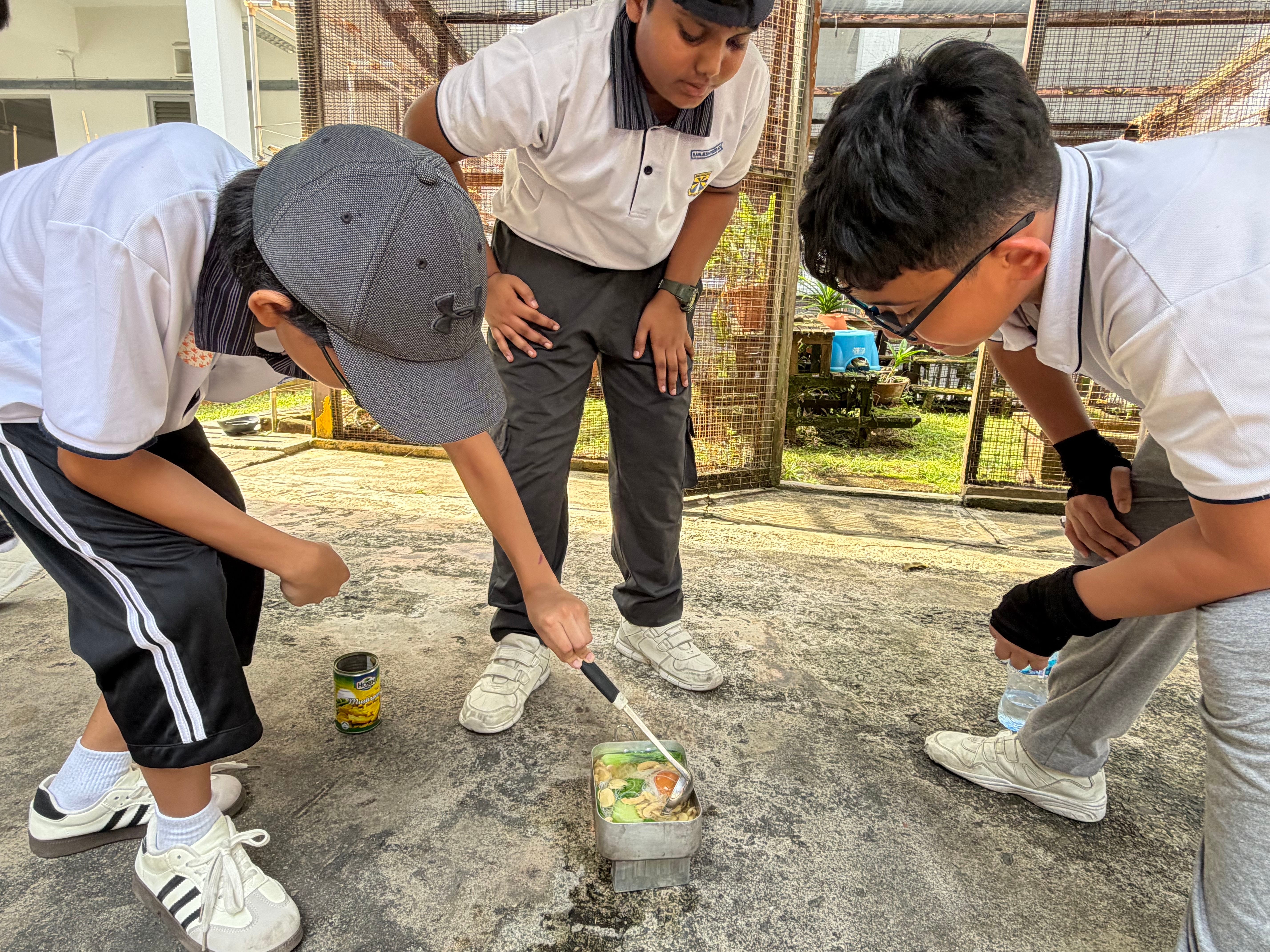 Camp cooking in action, as students work together to prepare their own meal over a portable stove.